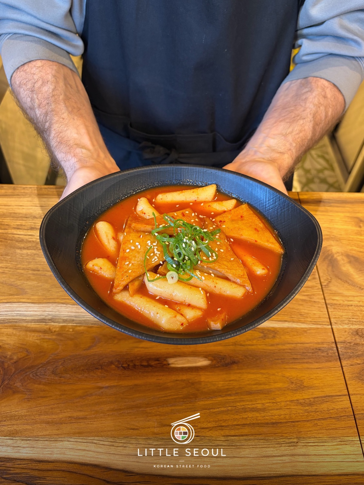 Hände halten eine Schale Tteokbokki